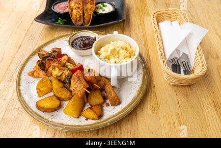 Pollo Shish Kebab, barbeque Shashlik, spiedini alla griglia con carne e verdura, frutta, peperoni, cipolle e ananas, servito con Coleslaw e. Foto Stock