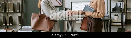 Donne d'affari che stringono la mano durante la riunione dell'ufficio Foto Stock