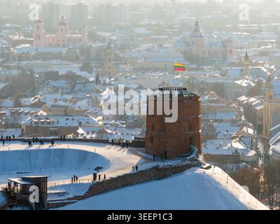 Vista aerea della Torre di Gediminas su una collina coperta di neve che si affaccia sui tetti storici e sulle cupole della chiesa della città nella contea di Vilnius, Lituania. Foto Stock