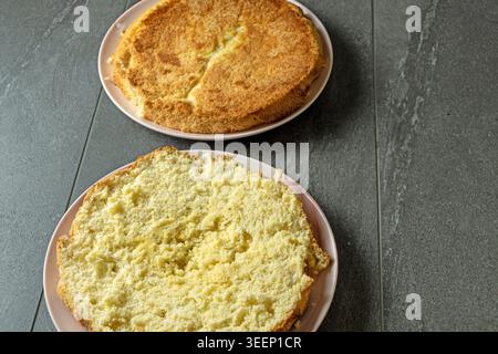 Torta di spugne fatta in casa appena sfornata tagliata a strati e preparata per assemblare una torta alla fragola in un vero ambiente di cucina casalingo. Foto Stock