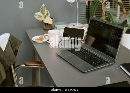Computer portatile che visualizza il codice sulla scrivania dell'ufficio domestico per il lavoro in remoto Foto Stock