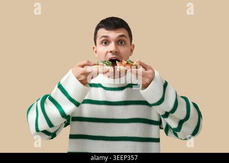Giovane con pezzi di gustosa pizza su sfondo beige Foto Stock