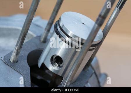Primo piano di un pistone del motore con fasce elastiche all'interno di un blocco motore aperto di una motocicletta di piccole dimensioni Foto Stock