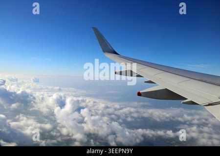 Vista dell'ala dell'aeromobile sopra le nuvole attraverso la finestra dell'aeromobile prima dell'atterraggio Foto Stock