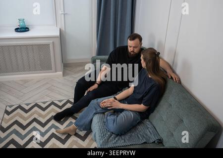 Coppia seduta sul divano, in conflitto o incomprensione, l'uomo e la donna sembrano sconvolti e ritirati, riflettendo le difficoltà del Foto Stock