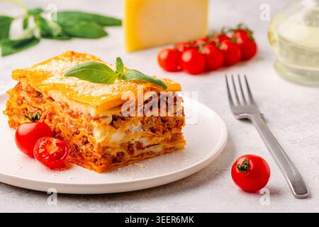 Lasagne tradizionali con salsa bolognese condite con foglie di basilico servite su un piatto bianco Foto Stock