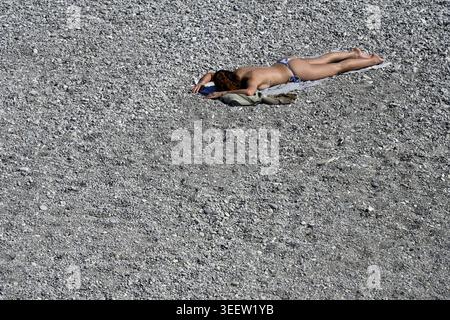 Donna in bikini che prende il sole sulla spiaggia di ciottoli Nizza Francia Foto Stock