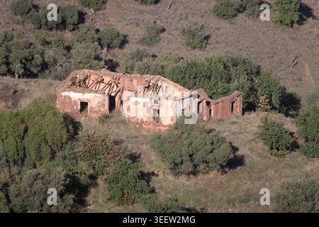 Rovina di una casa colonica senza tetto abbandonata immersa nel verde bosco di querce nelle sierras sopra San Juan, Malaga, Andalusia, Spagna. Foto Stock
