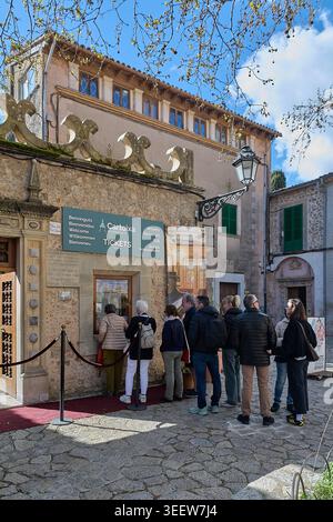 Maiorca, Spagna - 12 maggio 2026: Un gruppo di visitatori fa la fila alla biglietteria in pietra della Cartuja de Valldemossa, un monastero storico e culturale Foto Stock