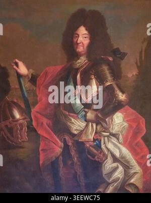 An oil portrait captures King Louis XIV clad in military armor with a red sash and ceremonial wig at the Chateau de Chambord, France. Foto Stock