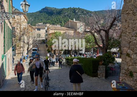 Maiorca, Spagna - 12 maggio 2026: Turisti e ciclisti esplorano le affascinanti strade acciottolate di Valldemossa, uno storico villaggio di montagna di Maiorca Foto Stock