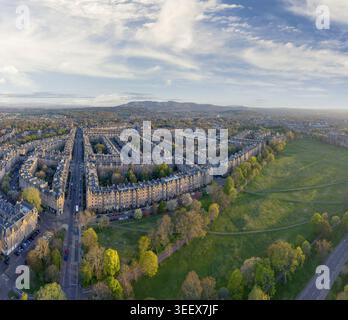 Vista aerea delle storiche case a schiera di pietra che confinano con un parco verde lussureggiante sotto un cielo blu morbido con colline lontane Edimburgo, Scozia, Regno Unito Foto Stock