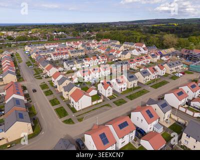 Vista aerea di una moderna residenza residenziale con case dal tetto rosso con pannelli solari e giardini verdi Edimburgo, Scozia, Regno Unito Foto Stock