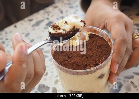 Gustando un dessert tiramisù con un cucchiaio in un ambiente accogliente Foto Stock