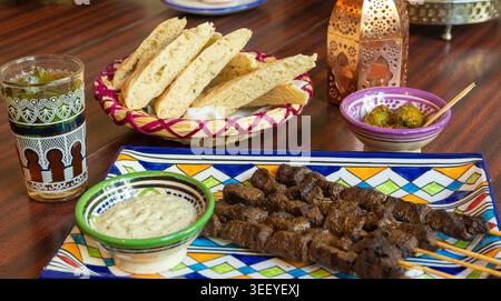Kebab di manzo marocchino su spiedini, cucina tradizionale araba, shashlik di montone, carne di vitello grigliata spiedata, griglia di agnello piccante con salsa bianca Foto Stock