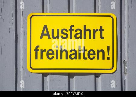 Gelbes Schild Ausfahrt freihalten an einem grauen Tor, Deutschland Foto Stock