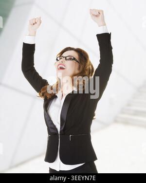Successo, donna d'affari vincitrice con pugni in alto Foto Stock