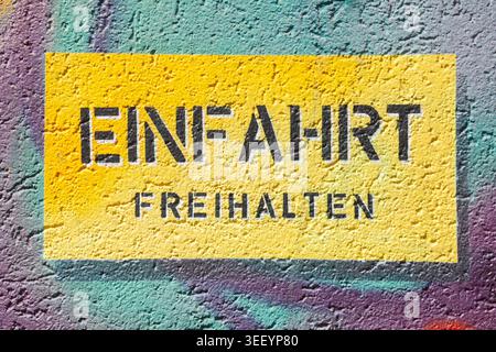 Gelbes Schild Einfahrt freihalten un einer bunt bemalten Mauer, Deutschland Foto Stock
