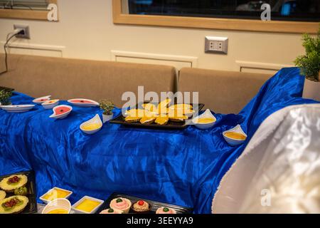 Buffet di dessert con una varietà di dolci, torte e dolcetti su un tavolo drappeggiato blu Foto Stock