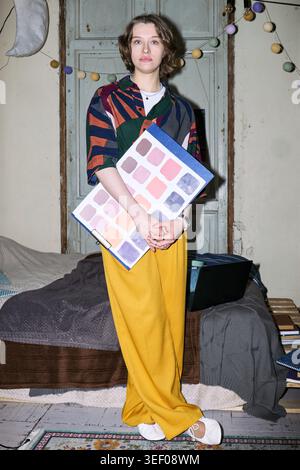 Ritratto di una giovane donna caucasica adulta che tiene la tavolozza dei colori e guarda la macchina fotografica, presentando un lavoro creativo di design. Utile per il branding, la direzione artistica, il portfolio creativo Foto Stock