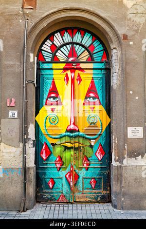 La Street art è esposta su una grande porta a Budapest in Ungheria. Il design colorato presenta un volto e varie forme. Foto Stock