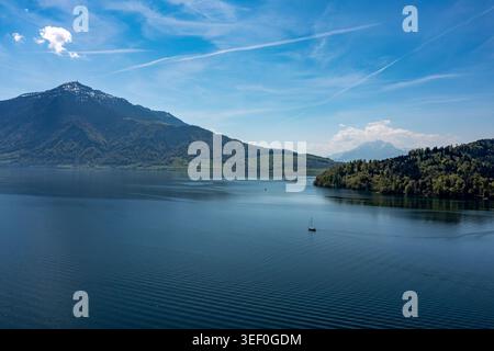 Vista panoramica aerea del Lago Zug e del Monte Rigi - barca a vela solitaria sulle acque blu calme sotto il cielo estivo Foto Stock