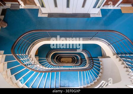 Vista dall'alto della scala a chiocciola blu con elegante balaustra in ferro - interni degli appartamenti di Budapest Foto Stock