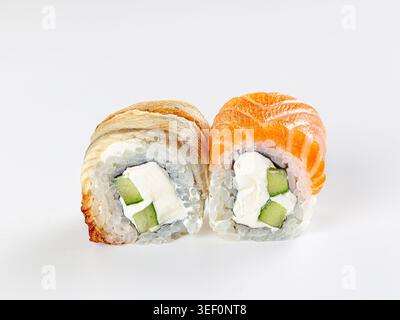 Primo piano di due freschi panini di sushi uramaki giapponesi. Una con salmone d'arancia, l'altra con l'anguilla. Ripieno di formaggio spalmabile e cetriolo. Cibo minimalista Foto Stock
