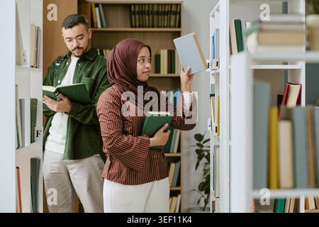 Donna musulmana e uomo che studiano nella Biblioteca per l'educazione dei migranti Foto Stock