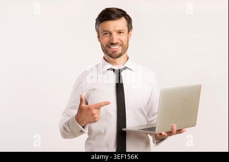 Uomo d'affari che punta al notebook mentre sorride in un ambiente professionale Foto Stock
