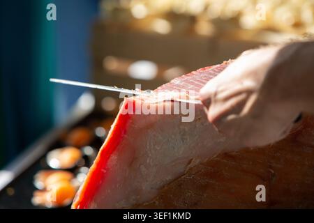 La mano dello chef affetta sottilmente un grosso pezzo di prosciutto stagionato Foto Stock