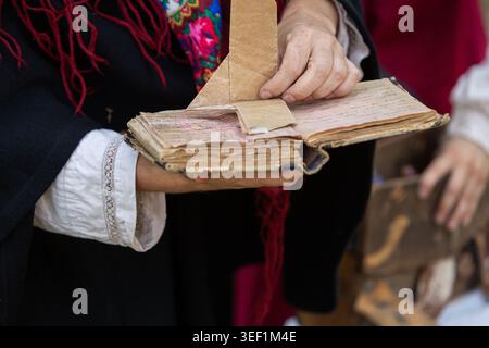 Indossa abiti tradizionali e apri un vecchio manuale vintage con pagine vecchie Foto Stock