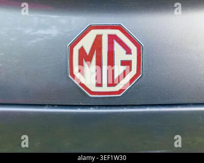 Primo piano di un logo MG rosso e crema montato su una carrozzeria metallica grigia Foto Stock