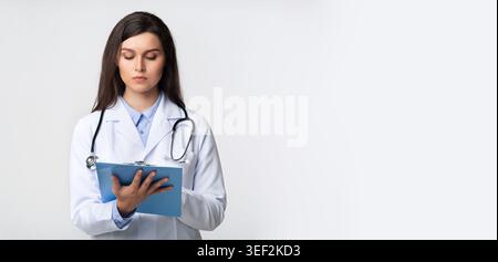 Professionista medico revisione dei file paziente in ambiente clinico con attenzione e attenzione Foto Stock