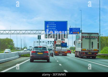 Paesi Bassi - 17 aprile 2026: Traffico pesante sull'autostrada A9 con segnaletica blu in alto per Utrecht, Amsterdam, Schiphol Airport, Rotterdam Foto Stock