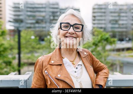 Donna matura sorridente godendo del paesaggio urbano Foto Stock