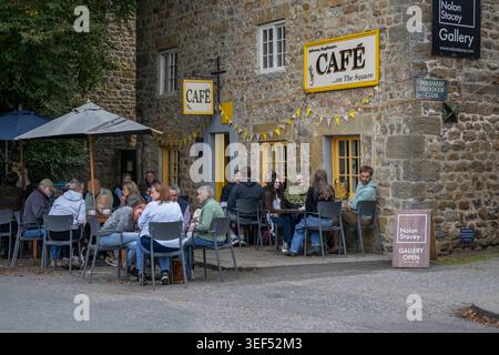 Persone che godono di rinfreschi, sedute, mangiare e bere all'aperto - sedute al Johnny Baghdads Cafe on the Square, Masham, North Yorkshire, Inghilterra, Regno Unito. Foto Stock