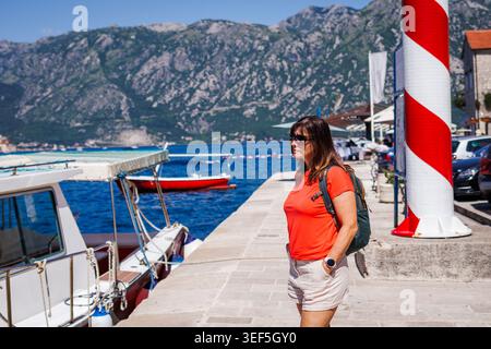 Donna viaggiatrice da sola che esplora la città di Cattaro in Montenegro. Turista femminile che guarda la baia del mare con le barche. Vacanze estive attive Foto Stock