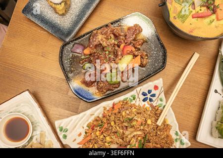 Cena STILL Life con un vassoio pieno di una deliziosa ricetta cinese per stufato di manzo con verdure e salsa, un piatto di riso e altre ricette Foto Stock