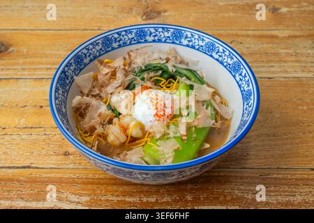 Il piatto presenta sottili tagliatelle di ramen ondulati in un brodo di miso piccante, coronato da mais dolce, burro fuso, alghe nori tritate e due fette di flam Foto Stock