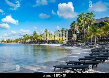 La spiaggia di Mambo a Curacao offre una perfetta scenografia di un resort caraibico, con numerose sedie a sdraio e palapas su sabbia bianca Foto Stock