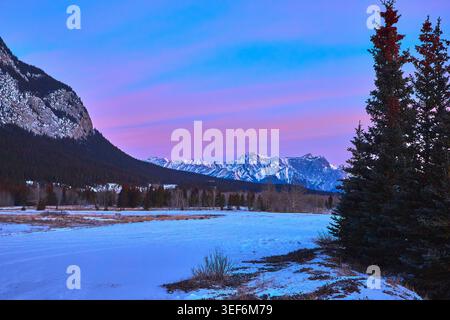 Alba invernale sulla Snowy Valley e sulla foresta Evergreen con le Majestic Mountain Peaks Foto Stock