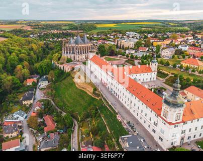 La Chiesa di Santa Barbara e il Collegio dei Gesuiti sono visti dall'alto al tramonto. Gli edifici storici si trovano su una collina circondata da alberi e dalla città di Kutna Hora in Cechia. Foto Stock