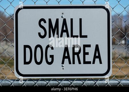 cartello metallico bianco e nero sulla recinzione a catena di un parco per cani Foto Stock