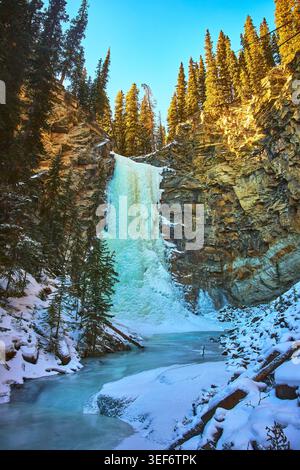 Cascata ghiacciata e fiume Snowy nel Winter Forest Canyon Alberta Foto Stock