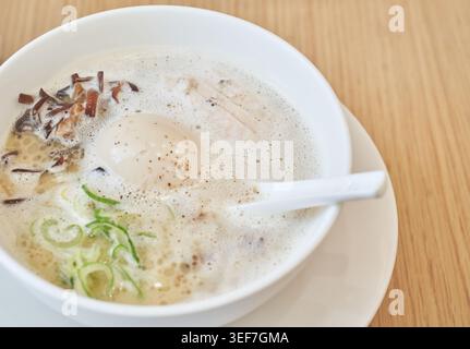 Ramen Paitan Tori cremoso con brodo di pollo schiumoso, uova sode, morbido chashu di pollo e spaghetti freschi catturati in appetitosi, luce intensa. Foto Stock