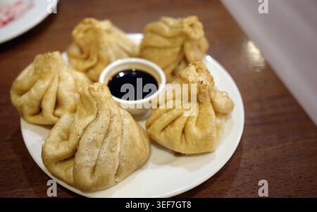 Autentici gnocchi di khinkali georgiani serviti su un piatto. Questo tradizionale piatto caucasico presenta sacchetti di pasta ritorto ripieni di carne speziata. Ideale Foto Stock