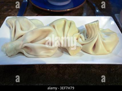 Autentici gnocchi di khinkali georgiani serviti su un piatto. Questo tradizionale piatto caucasico presenta sacchetti di pasta ritorto ripieni di carne speziata. Ideale Foto Stock