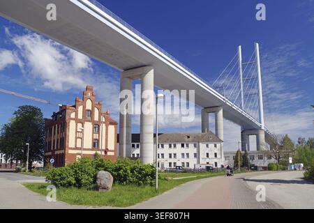 Ponte moderno che attraversa la strada circondato da edifici storici e cieli limpidi, Ruegen Bridge, Stralsund, Meclemburgo-Pomerania Occidentale, Germania Foto Stock
