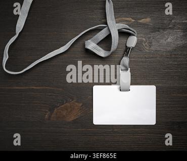 Badge id in plastica vuoto con cordone su superficie in legno. Scheda id vuota. Posizione piatta Foto Stock
